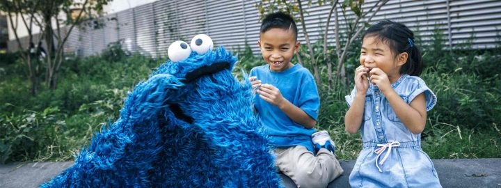 Cookie Monster and child laughing together.