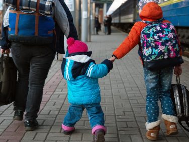 Parent with two kids walking in a train station depot.