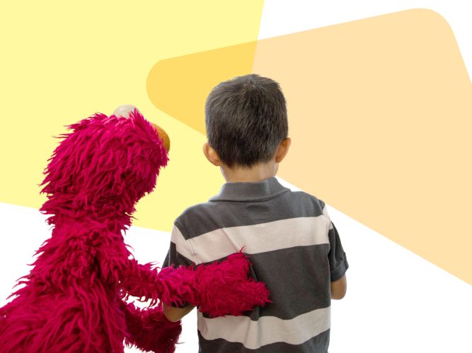 Elmo with his hand on the back of a child looking away.