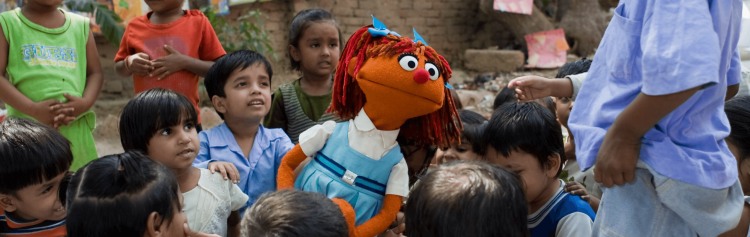 A young muppet girl poses amongst a group of children.