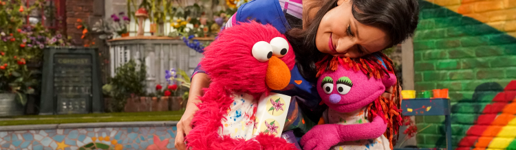 Nina gives Elmo and Lily a big hug.