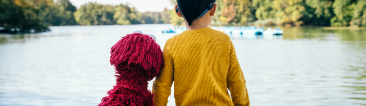 Elmo and child looking at a lake.