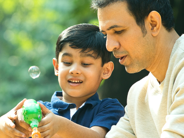 A father helps his son blow bubbles